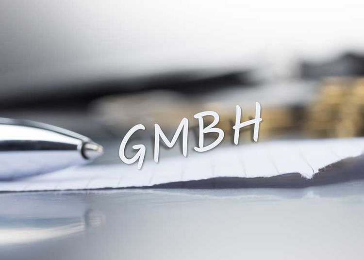 Die Bildcollage zeigt einen Tisch, auf dem ein Blatt Papier, ein Kugelschreiber und im Hintergrund Euro-Münzen liegen. Über dem Papier schwebt der Schriftzug „GmbH”.