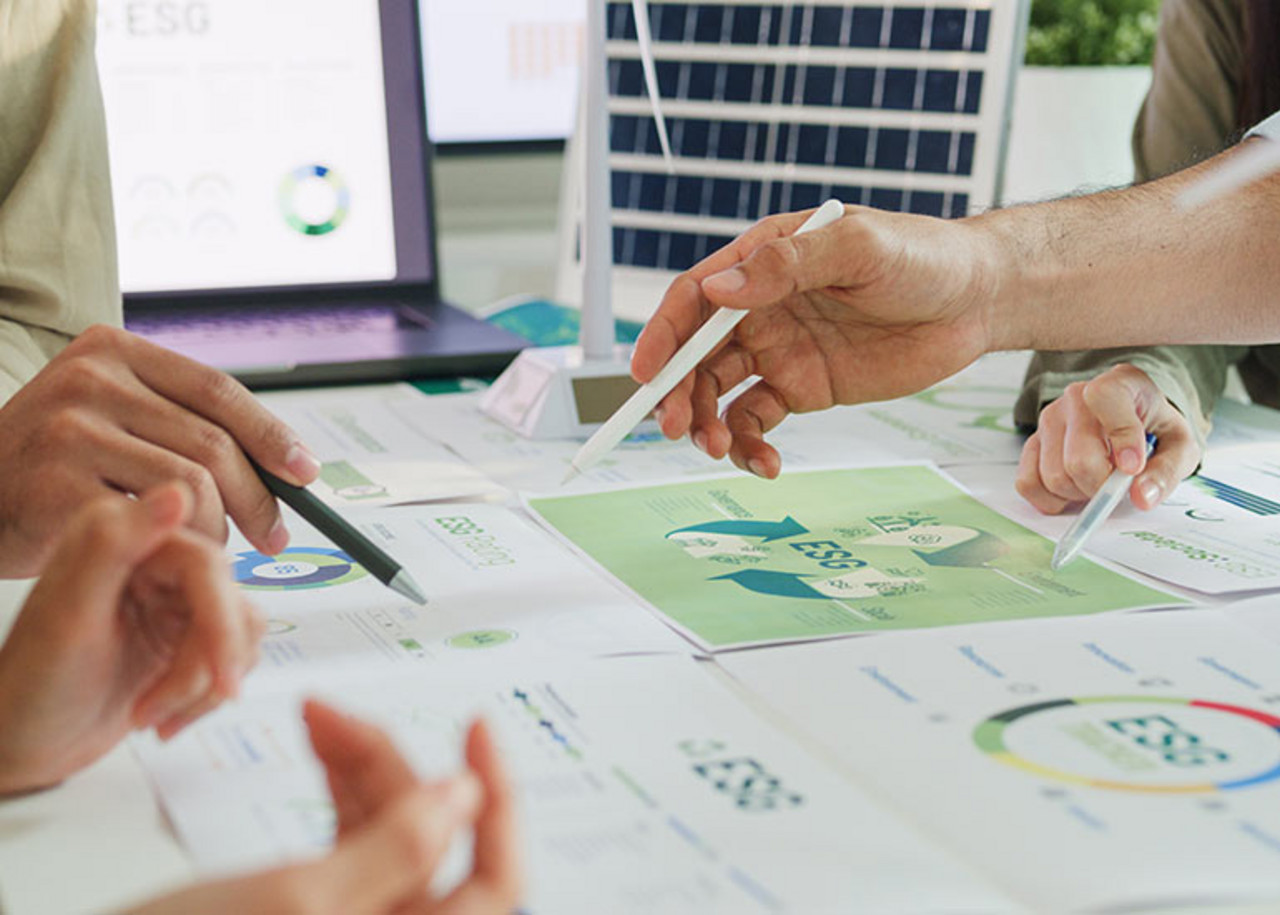Personen sitzen zusammen und diskutieren ESG-Berichte.