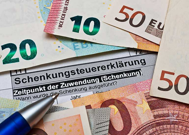 Auf einer Schenkungssteuererklärung liegen Euro-Banknoten und ein Kugelschreiber.