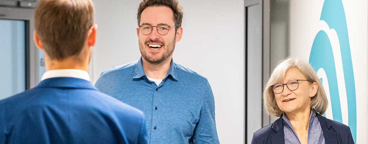 Drei Personen treffen sich auf dem Flur eines Nexia-Büros.