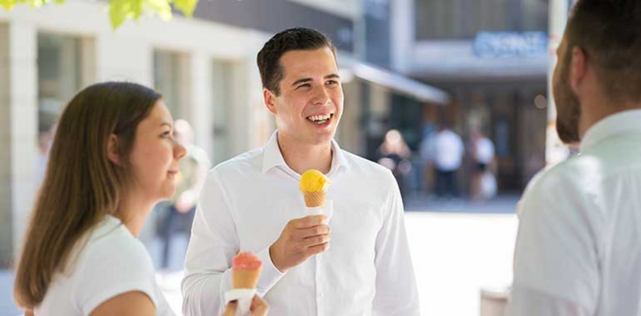 Persönlicher Eindruck unserer Standorte gefällig? Draußen stehen drei Personen zusammen und essen ein Eis.