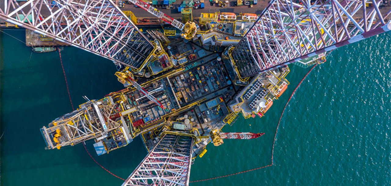 Blick auf eine Verladestation im Meer. Container und Kräne sind zu sehen.