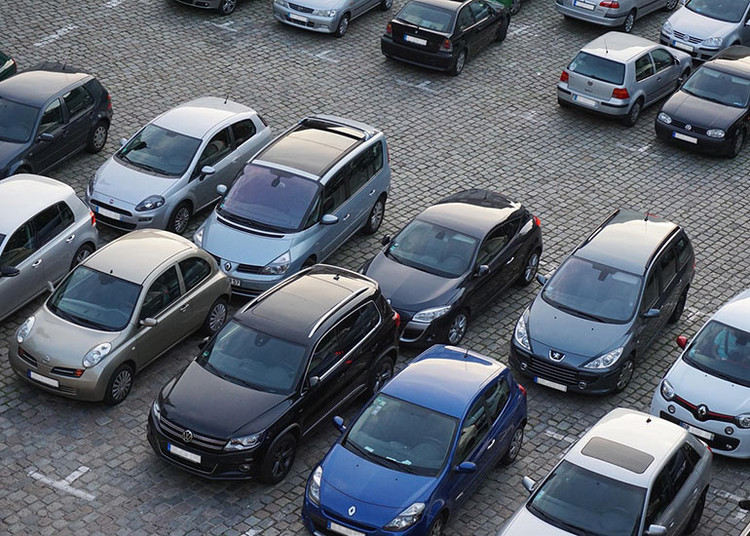 Auf dem Bild ist ein Parkplatz mit vielen parkenden Autos zu sehen.