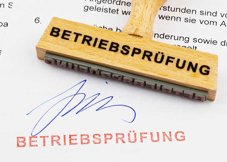 Auf einem Blatt Papier, auf dem der Ausdruck „Betriebsprüfung” abgedruckt ist, liegt ein Stempel mit derselben Aufschrift.