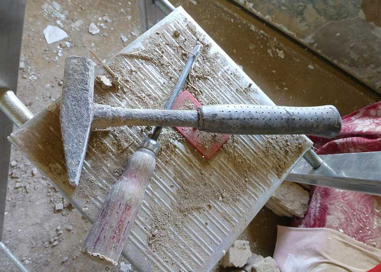 Auf einer Baustelle liegen ein Hammer und ein Schraubenzieher auf einer Leiter.