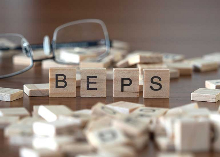 Der Begriff "BEPS" steht für Base Erosion and Profit Shifting. Die Buchstaben "BEPS" stehen jeweils auf einem Holzwürfel auf einem Tisch. Daneben liegen weitere Holzwürfel. Im Hintergrund liegt eine Brille.