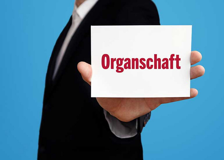Eine Person hält einen Zettel in Form einer Visitenkarte mit der Aufschrift "Organschaft".