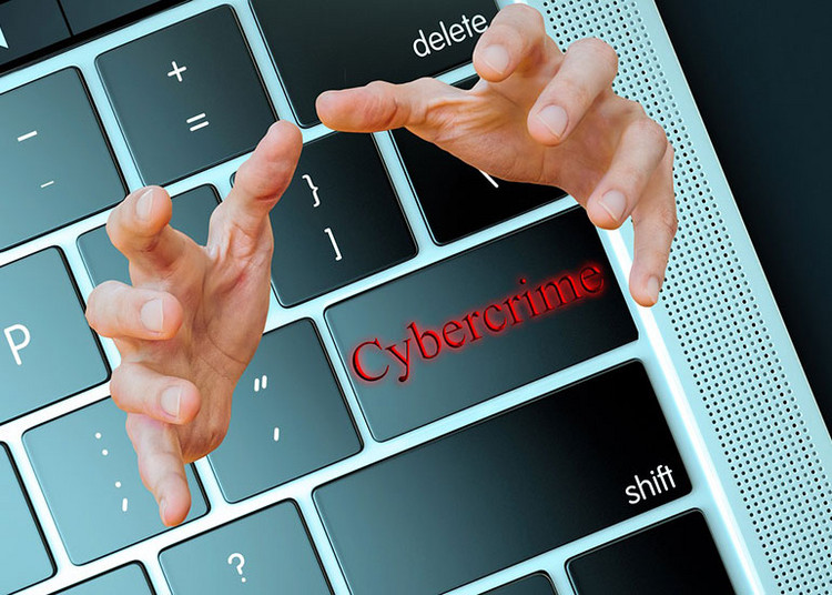 Die Bildcollage zeigt eine Tastatur mit einer Taste, auf der „Cybercrime” steht. Darüber hinaus ragen zwei Hände aus der Tastatur, die sich dem Betrachter entgegenstrecken.
