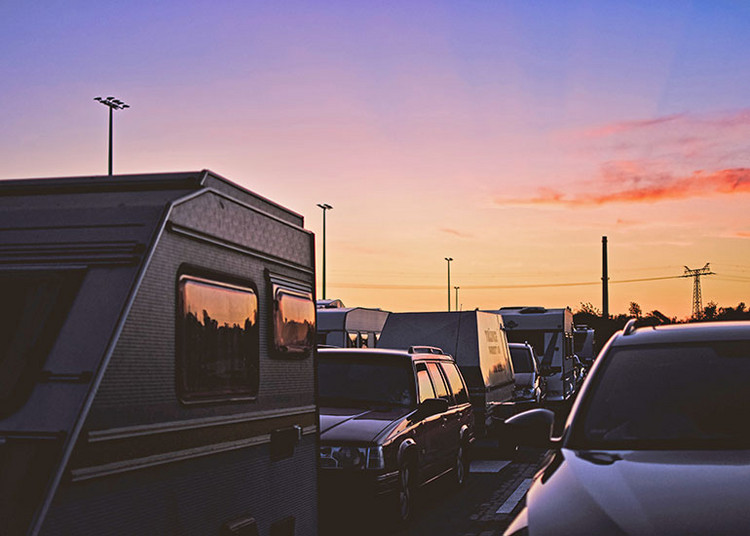 Mehrere Wohnmobile und Fahrzeuge stehen im Stau bei Sonnenuntergang.