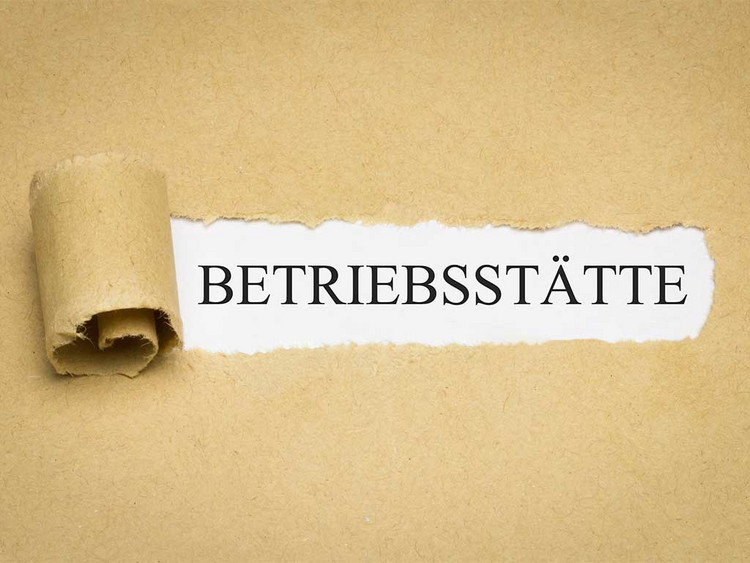 Aufgerissenes Papier mit dem Schriftzug "Betriebsstätte" auf weißem Hintergrund.