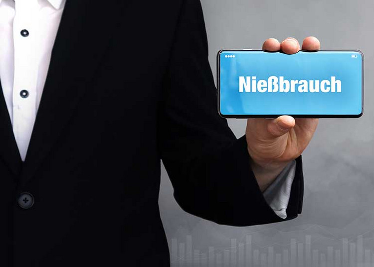 Eine Person hält ein Mobiltelefon in der Hand, auf dessen Display „Nießbrauch“ steht.
