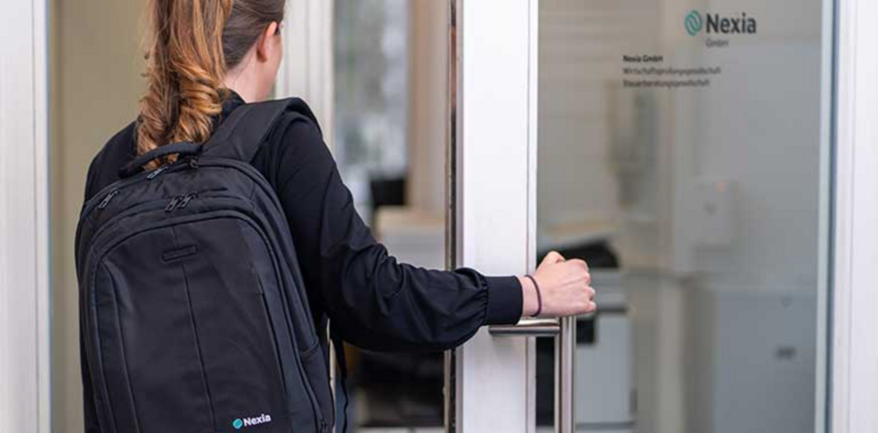 Eine Person mit einem Nexia Rucksack betritt das Büro durch eine Tür.