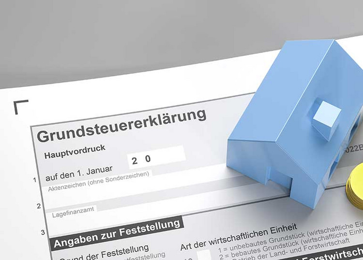 Auf einem Formular einer Grundsteuererklärung steht ein Modell eines Hauses.