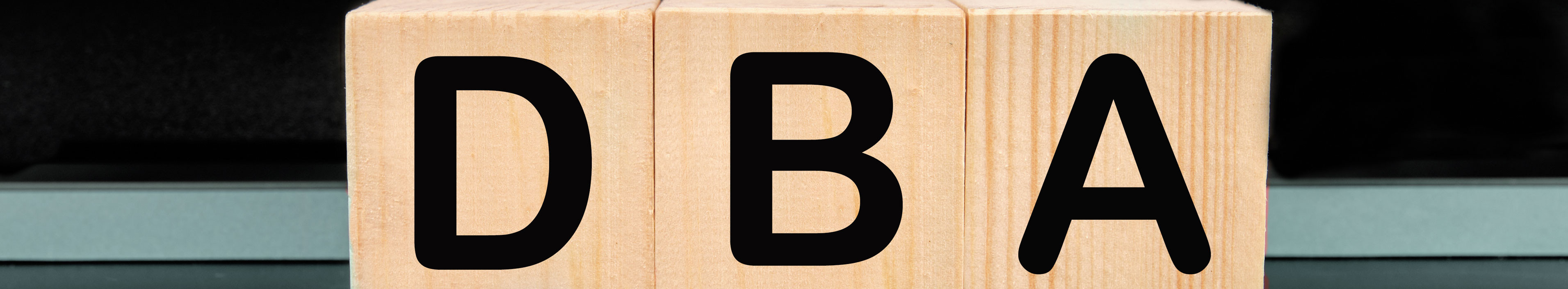 Auf 3 Holzklötzen steht "DBA" für “Doppelbesteuerungsabkommen”. Die Buchstaben stehen jeweils auf einem Holzklotz.