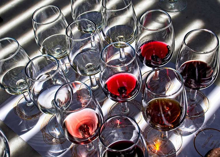 Viele Rotweingläser stehen leer bis halb voll auf einem Tisch.