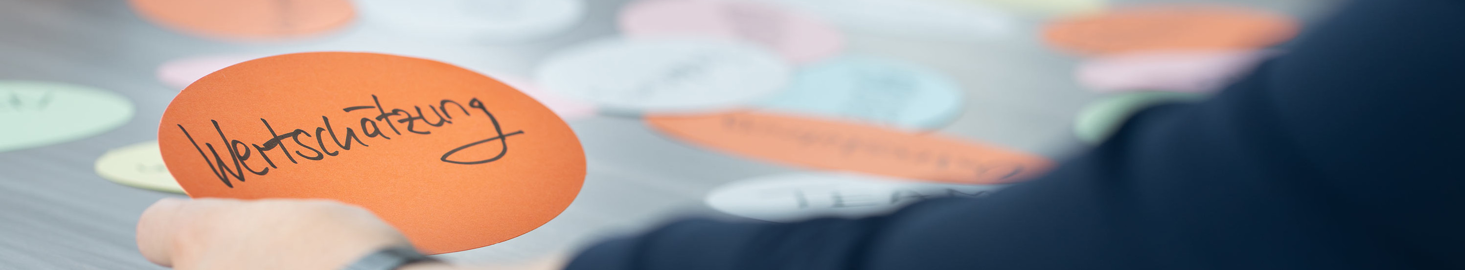 Person sitzt am Tisch und hält eine Karte mit der Aufschrift "Wertschätzung".