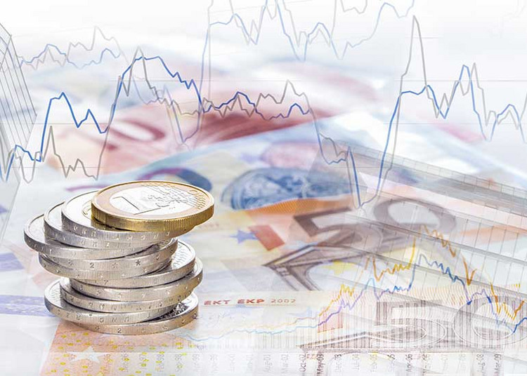 Gestapelte Euro-Münzen auf Euro-Banknoten vor einem Hintergrund mit dargestellten Finanz- und Kursdiagrammen.