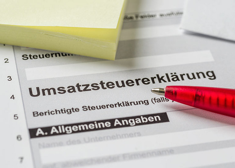 Auf dem Formular der Umsatzsteuererklärung liegen ein Post-it-Block und ein Kugelschreiber.