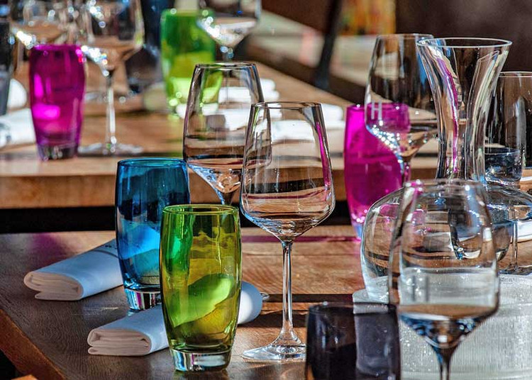 In einem Restaurant stehen gedeckte Tische mit vielen Gläsern.