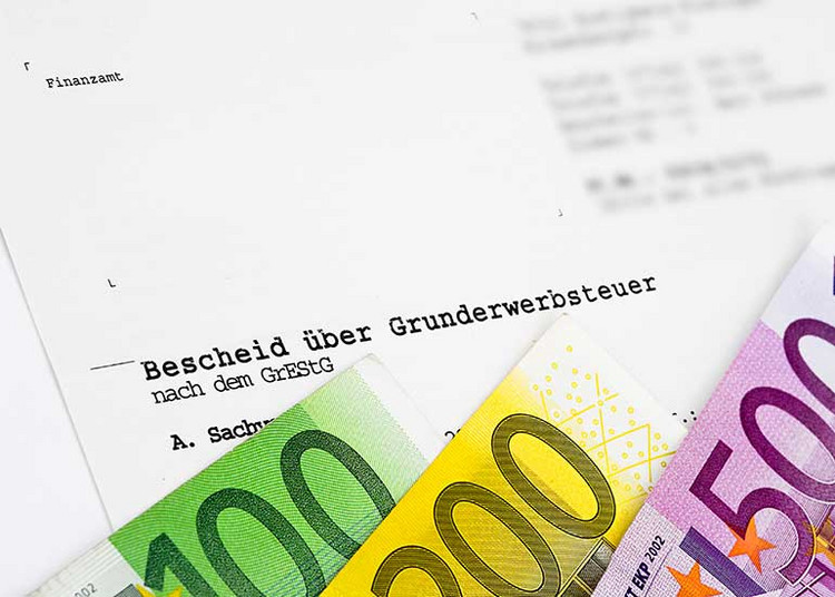 Euro-Scheine vor einem Bescheid über Grunderwerbsteuer.