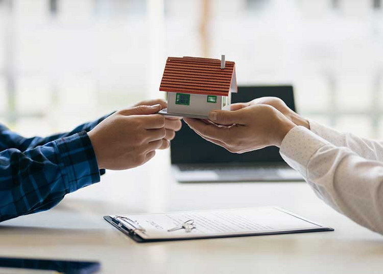 Ehegatten-GbR: Familienheim bleibt schenkungsteuerfrei Eine Person übergibt einer anderen ein Modellhaus.