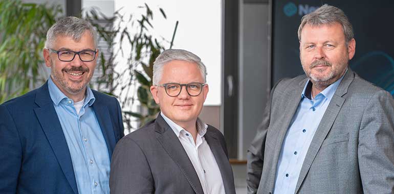 Drei Partner stehen nebeneinander und lachen.
