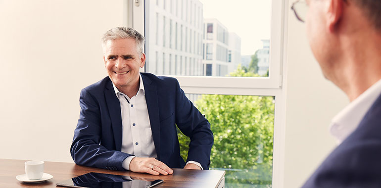 Zwei Partner sitzen an einem Tisch und unterhalten sich.