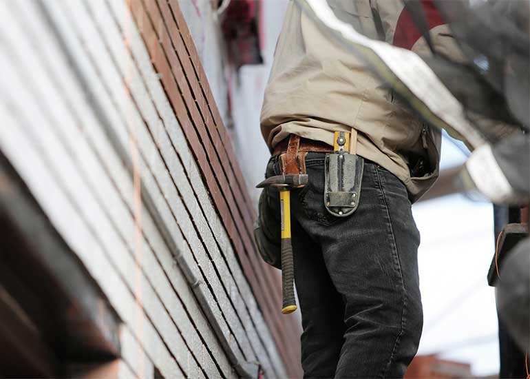 Handwerker bei der Arbeit neben einem Haus.