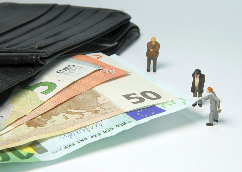Aus einem Portemonnaie ragen Euro-Banknoten. Neben den Scheinen stehen kleine Figuren von Personen.