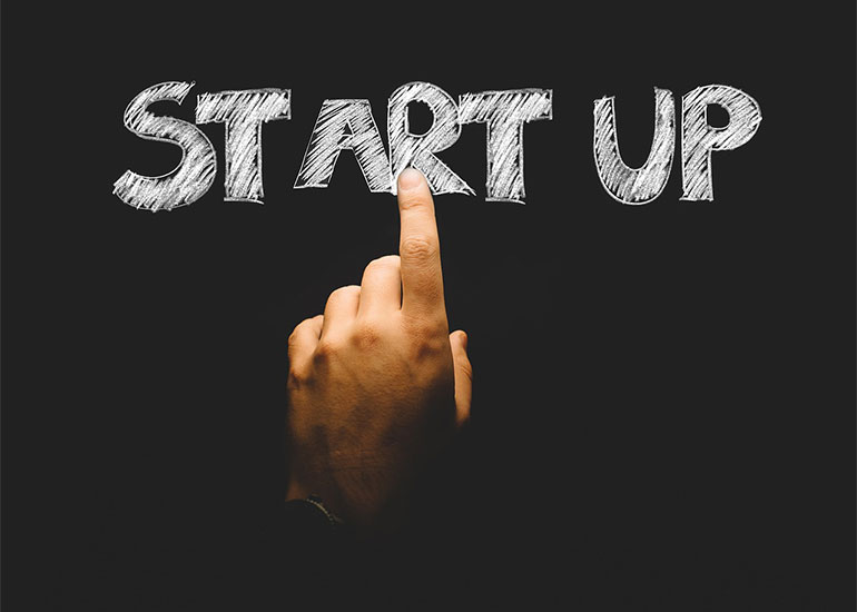 Eine Hand berührt mit dem Zeigefinger einen virtuellen Schriftzug, auf dem "Start Up" zu lesen ist.