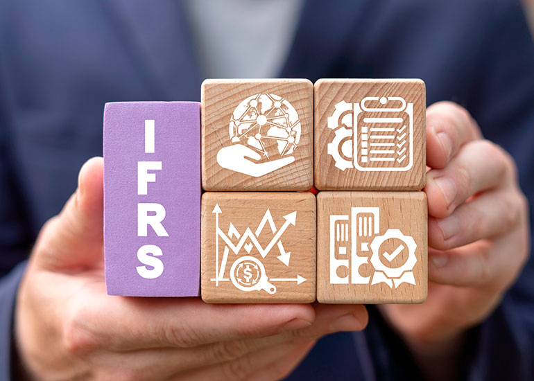 Auf einem Würfel steht „IFRS“ für „International Financial Reporting Standards“. Daneben befinden sich weitere Würfel mit Grafiken zu diesem Thema.