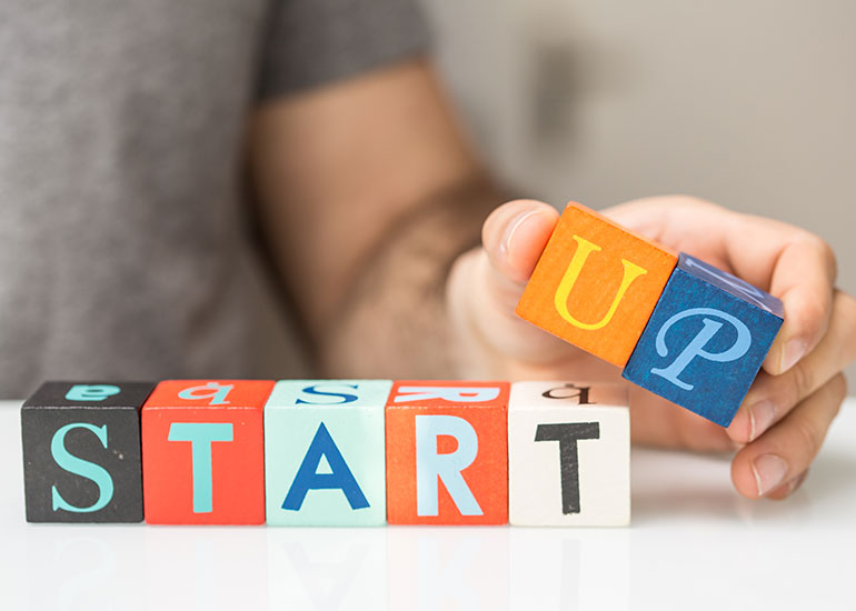 Eine Person hat mit Würfeln, die jeweils einen Buchstaben zeigen, das Wort "Start" geschrieben und ergänzt das ebenfalls mit Würfeln geschriebene Wort "Up".
