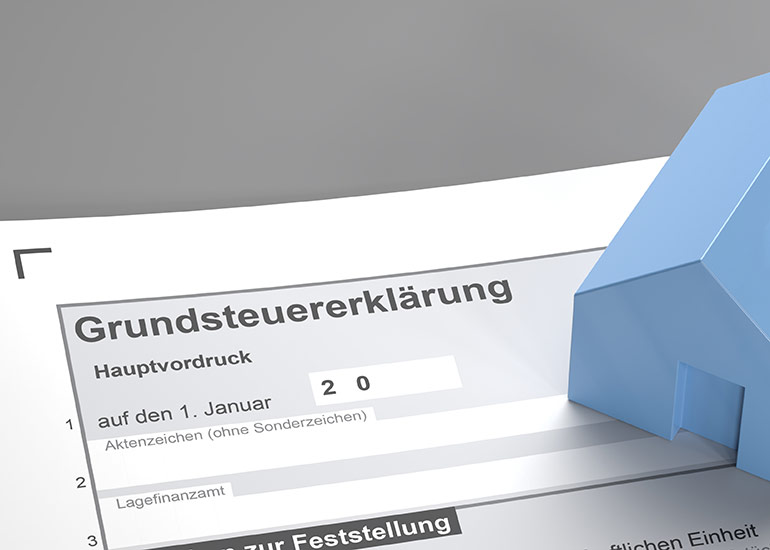 Formular für die Grundsteuererklärung. Auf dem Formular steht ein Modell eines Hauses.