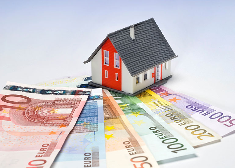 Ein Modell eines Hauses steht auf Euro-Banknoten.