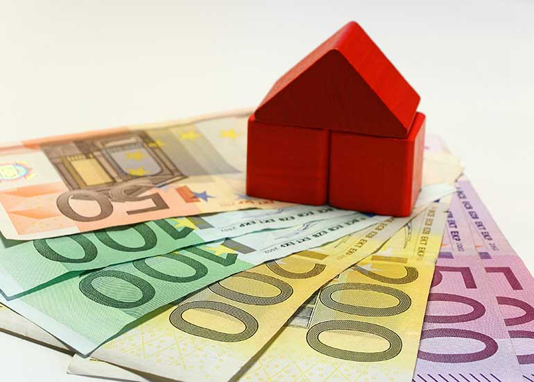 Auf Euro-Banknoten steht ein Modell eines Hauses.