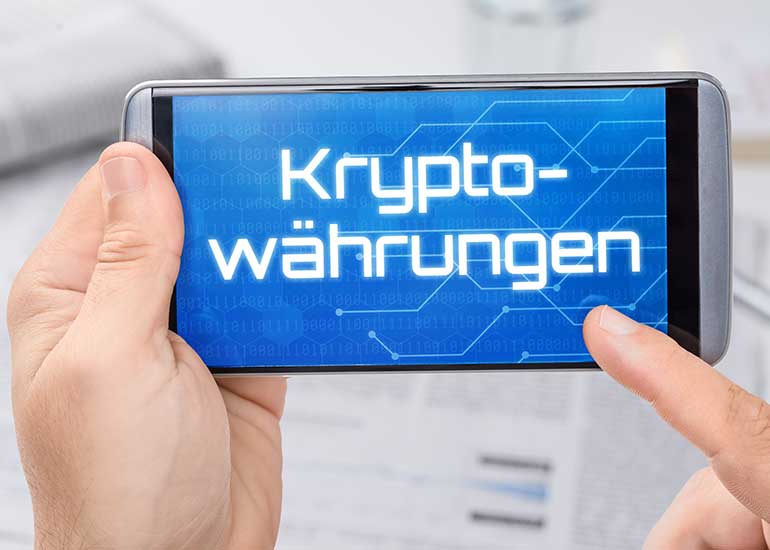 Eine Person hält ein Smartphone mit dem Text „Kryptowährungen” auf dem Display.