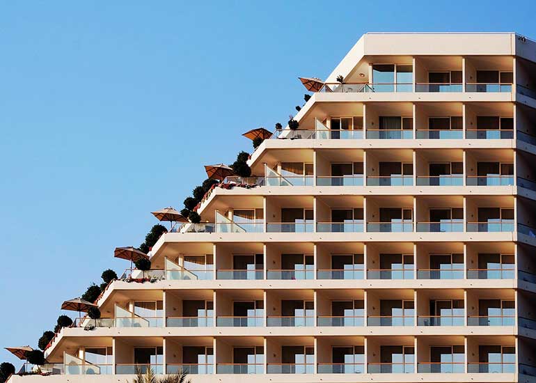 Blick auf ein Haus. Es hat viele Wohneinheiten. Jede hat einen Balkon.