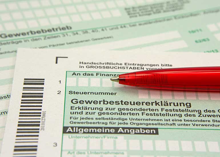 Zu sehen ist ein Ausschnitt aus einer Gewerbesteuererklärung. Auf den Formularen liegt ein Kugelschreiber.