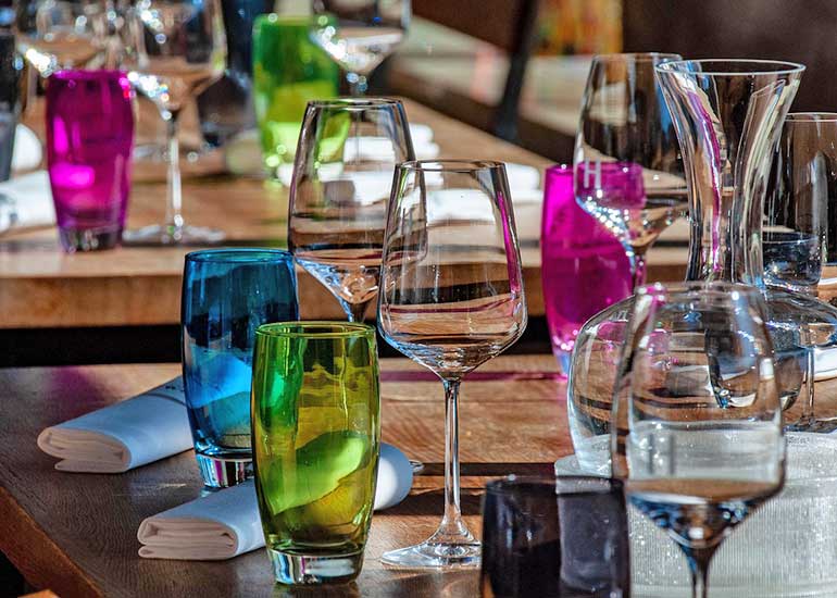 In einem Restaurant stehen gedeckte Tische mit vielen Gläsern.