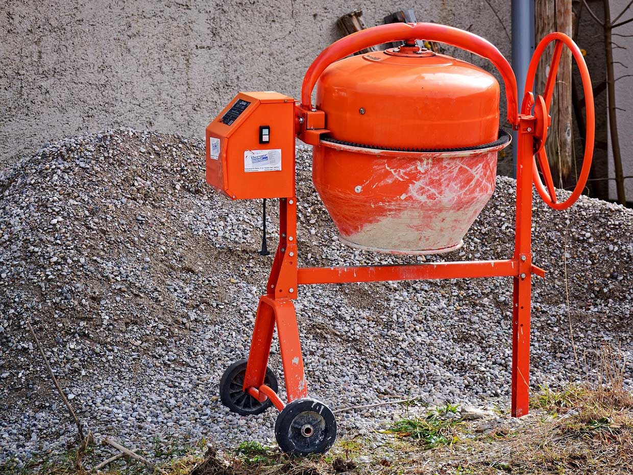Vor einem Haufen aus kleinen Steinen steht ein Betonmischer.