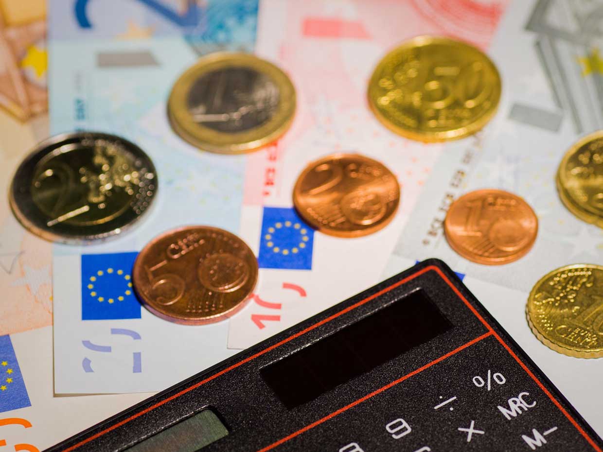 Auf Euro-Banknoten liegen ein Taschenrechner und Euro-Münzen.