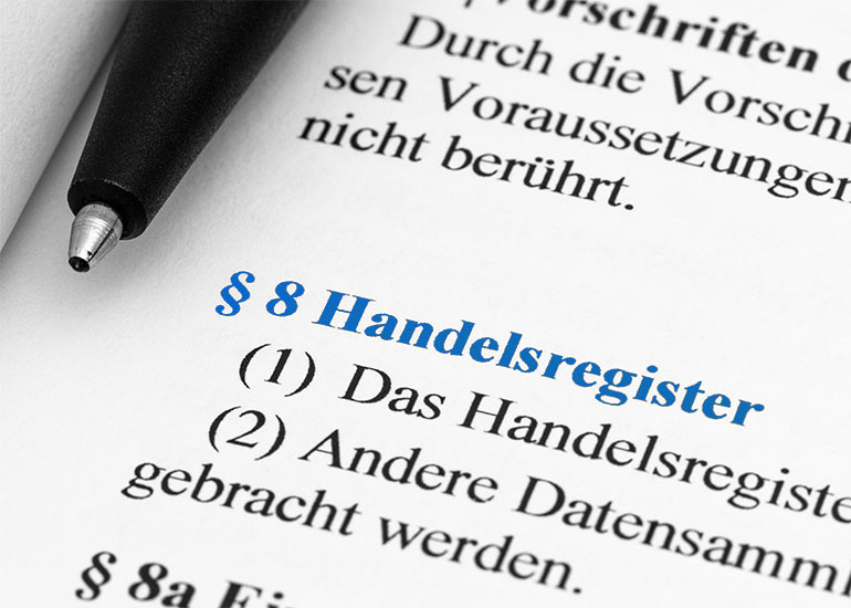In einem Buch ist der Absatz zu „§ 8 Handelsregister” hervorgehoben. Daneben liegt ein Kugelschreiber.