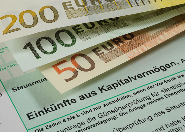 Ausschnitt eines Formulars zu „Einkünfte aus Kapitalvermögen”. Darauf liegen Euro-Banknoten.