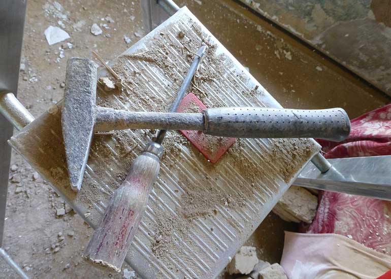 Auf einer Baustelle liegen ein Hammer und ein Schraubenzieher auf einer Leiter.