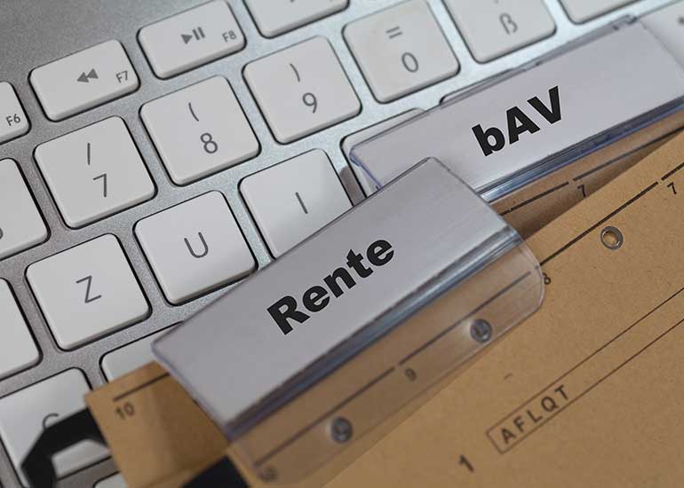 Auf einer Tastatur liegen Ordner mit Registern, auf denen die Aufschriften „Rente” und „bAV” stehen.