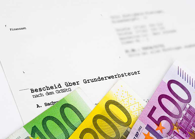 Euro-Scheine vor einem Bescheid über Grunderwerbsteuer.