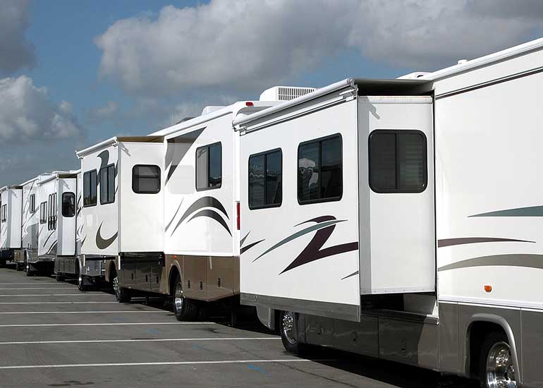 Blick auf viele Wohnwagen, die in einer Reihe auf einem Parkplatz stehen.