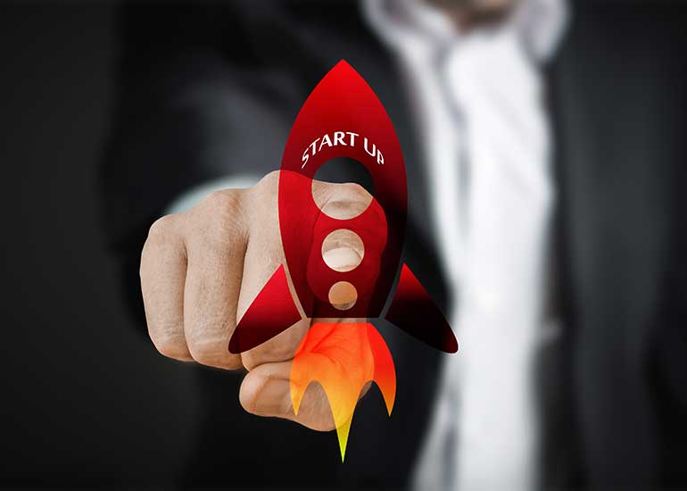 In der Bildcollage berührt eine Hand mit dem Zeigefinger eine Grafik einer Rakete, auf der der Schriftzug „Start Up” zu lesen ist.