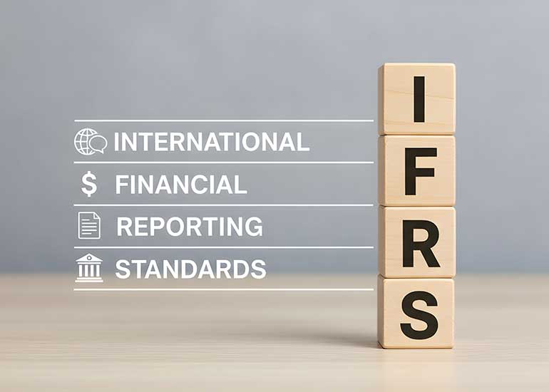 Die Bildcollage zeigt vier übereinandergestapelte Holzbausteine, die das Akronym „IFRS“ bilden. Daneben steht die ausgeschriebene Bezeichnung „International Financial Reporting Standards“. Ergänzende Symbole für globale Finanzberichterstattung, Dokumentation und Regulierung verdeutlichen den Bezug zu internationalen Rechnungslegungsstandards. Das Bild wurde mithilfe von KI erstellt.