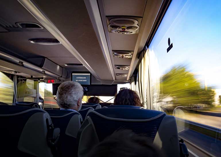 Innenansicht eines Reisebusses während der Fahrt mit Blick auf vorbeiziehende Landschaft.